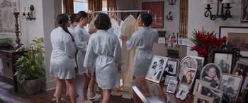 Movie still from “Father of the Bride” (2022), directed by Gary Alazraki – A group of women in robes standing in front of a clothing rack; Wide shot, Over the shoulder angle