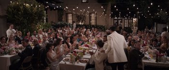 Movie still from “Father of the Bride” (2022), directed by Gary Alazraki – A group of people sitting at a table with food; Wide shot, High angle