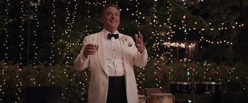Movie still from “Father of the Bride” (2022), directed by Gary Alazraki – A man in a white tuxedo holding a glass of wine; Medium shot, Over the shoulder angle