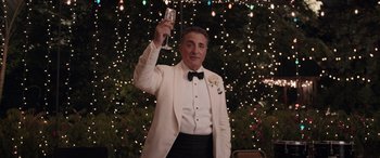 Movie still from “Father of the Bride” (2022), directed by Gary Alazraki – A man in a tuxedo holding up a glass of champagne; Medium shot, Low angle