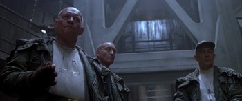 Movie still from “Alien³” (1992), directed by David Fincher – Two men standing next to each other in front of a building; Medium shot, Low angle