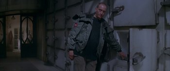 Movie still from “Alien³” (1992), directed by David Fincher – A man wearing a jacket standing next to a wall; Medium shot, Low angle