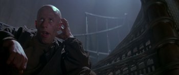 Movie still from “Alien³” (1992), directed by David Fincher – An older man talking on a cell phone in front of a building; Close Up shot, Low angle