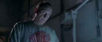 Movie still from “Alien³” (1992), directed by David Fincher – A bald man with blood on his shirt; Close Up shot, Over the shoulder angle