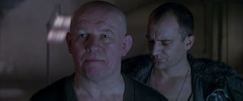 Movie still from “Alien³” (1992), directed by David Fincher – A man with a shaved head is listening to music while another man looks on; Close Up shot, Low angle