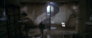 Movie still from “Alien³” (1992), directed by David Fincher – A man walking down a spiral staircase in a building; Extreme Wide shot, High angle