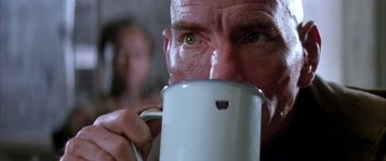 Movie still from “Alien³” (1992), directed by David Fincher – An older man drinking from a white mug; Extreme Close Up shot, Over the shoulder angle