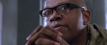 Movie still from “Alien³” (1992), directed by David Fincher – A person wearing glasses with their hands on his chin; Close Up shot, Low angle