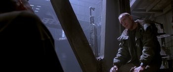 Movie still from “Alien³” (1992), directed by David Fincher – A man standing next to a window in a room; Medium shot, Low angle