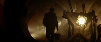 Movie still from “Alien³” (1992), directed by David Fincher – A man holding a bag in a tunnel; Wide shot, Low angle