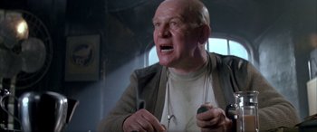 Movie still from “Alien³” (1992), directed by David Fincher – An older man with a bald head is holding a microphone; Close Up shot, Low angle