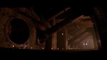 Movie still from “Alien³” (1992), directed by David Fincher – A dark picture of a room that has candles in it; Extreme Wide shot, Low angle