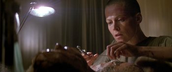 Movie still from “Alien³” (1992), directed by David Fincher – A person that is getting a tattoo on his arm; Close Up shot, Low angle