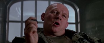 Movie still from “Alien³” (1992), directed by David Fincher – A bald man holding a cell phone up to his mouth; Close Up shot, Low angle