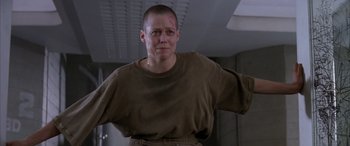 Movie still from “Alien³” (1992), directed by David Fincher – A man in a brown shirt is standing in a room; Medium shot, Low angle