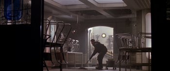 Movie still from “Alien³” (1992), directed by David Fincher – A man sweeping the floor in a room with chairs; Wide shot, Low angle