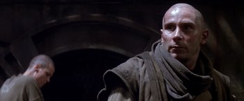 Movie still from “Alien³” (1992), directed by David Fincher – A bald man in a black and brown jacket; Close Up shot, Low angle