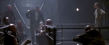 Movie still from “Alien³” (1992), directed by David Fincher – Two men are sitting in a boxing ring and one is holding a sword; Wide shot, Low angle
