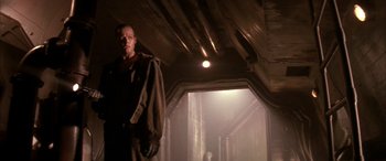 Movie still from “Alien³” (1992), directed by David Fincher – A man standing inside of a building in the dark; Medium shot, Low angle