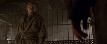 Movie still from “Alien³” (1992), directed by David Fincher – A man standing in front of a metal fence; Medium shot, Low angle