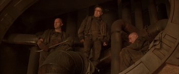 Movie still from “Alien³” (1992), directed by David Fincher – A man in a black jacket standing next to another man; Medium shot, Low angle