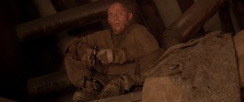 Movie still from “Alien³” (1992), directed by David Fincher – A man sitting on top of a building wearing safety gear; Medium shot, Low angle