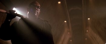Movie still from “Alien³” (1992), directed by David Fincher – A man with glasses is standing in a dark room; Close Up shot, Low angle