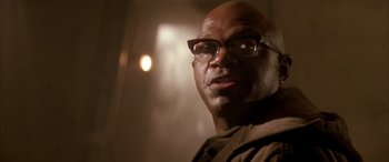 Movie still from “Alien³” (1992), directed by David Fincher – A bald man wearing glasses looking at the camera; Close Up shot, Low angle