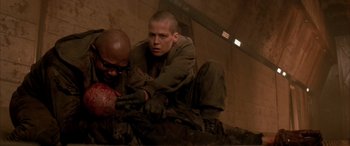 Movie still from “Alien³” (1992), directed by David Fincher – A man is holding another man's arm in a room; Medium shot, Over the shoulder angle