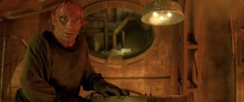 Movie still from “Alien³” (1992), directed by David Fincher – A man in a brown shirt is working in a workshop; Medium shot, High angle