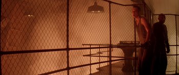 Movie still from “Alien³” (1992), directed by David Fincher – A view of a prison cell through a chain link fence; Extreme Wide shot, High angle