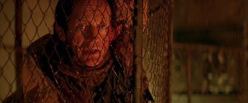 Movie still from “Alien³” (1992), directed by David Fincher – A man looking through a chain link fence at night; Close Up shot, Overhead angle
