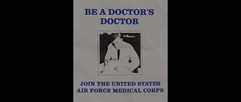 Movie still from “Fauci” (2021), directed by John Hoffman – A poster with a picture of a man in a white lab coat; Extreme Close Up shot, Overhead angle