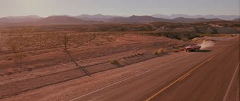 Movie still from “Fear and Loathing in Las Vegas” (1998), directed by Terry Gilliam – An empty desert road with mountains in the background; Extreme Wide shot, High angle