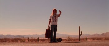 Movie still from “Fear and Loathing in Las Vegas” (1998), directed by Terry Gilliam – A person standing on the side of a road holding a bag; Wide shot, Low angle