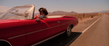 Movie still from “Fear and Loathing in Las Vegas” (1998), directed by Terry Gilliam – A man driving a red car down a street; Wide shot, Low angle