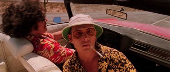 Movie still from “Fear and Loathing in Las Vegas” (1998), directed by Terry Gilliam – A man with a hat smoking a cigarette in the backseat of a car; Close Up shot, Low angle