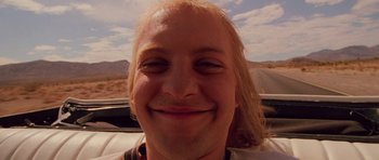 Movie still from “Fear and Loathing in Las Vegas” (1998), directed by Terry Gilliam – A man with long blonde hair smiling for the camera; Close Up shot, Low angle