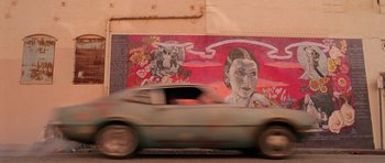 Movie still from “Fear and Loathing in Las Vegas” (1998), directed by Terry Gilliam – A car driving past a mural on the side of a building; Wide shot, Low angle