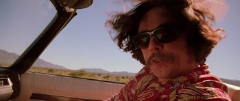 Movie still from “Fear and Loathing in Las Vegas” (1998), directed by Terry Gilliam – A man in a red shirt and sunglasses driving a car; Close Up shot, Low angle
