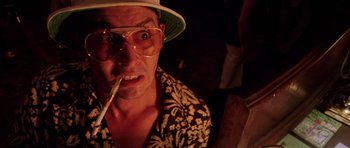 Movie still from “Fear and Loathing in Las Vegas” (1998), directed by Terry Gilliam – A man wearing a hat and glasses smoking a cigarette; Close Up shot, Low angle
