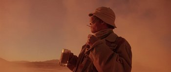 Movie still from “Fear and Loathing in Las Vegas” (1998), directed by Terry Gilliam – A man holding a glass of beer while smoking a cigarette; Medium shot, Low angle