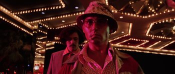 Movie still from “Fear and Loathing in Las Vegas” (1998), directed by Terry Gilliam – A man in a hat smoking a pipe in front of another man; Close Up shot, Low angle