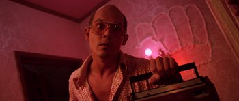 Movie still from “Fear and Loathing in Las Vegas” (1998), directed by Terry Gilliam – A man in a pink shirt and sunglasses holding a pink light; Close Up shot, Low angle
