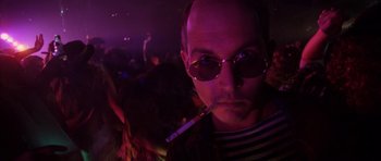 Movie still from “Fear and Loathing in Las Vegas” (1998), directed by Terry Gilliam – A man with a cigarette in his mouth in a dark room; Close Up shot, Low angle