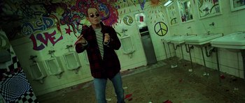 Movie still from “Fear and Loathing in Las Vegas” (1998), directed by Terry Gilliam – A man wearing a jacket and sunglasses in a bathroom; Wide shot, Overhead angle