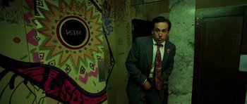 Movie still from “Fear and Loathing in Las Vegas” (1998), directed by Terry Gilliam – A man in a suit standing in front of a wall with graffiti; Medium shot, Low angle