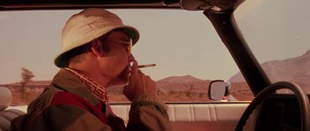 Movie still from “Fear and Loathing in Las Vegas” (1998), directed by Terry Gilliam – A man smoking a cigarette while sitting in the passenger seat of a car; Close Up shot, Low angle