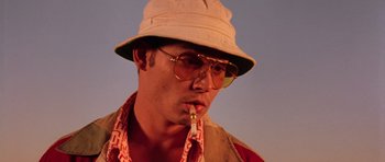 Movie still from “Fear and Loathing in Las Vegas” (1998), directed by Terry Gilliam – A man wearing a hat and glasses smoking a pipe; Close Up shot, Low angle
