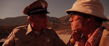 Movie still from “Fear and Loathing in Las Vegas” (1998), directed by Terry Gilliam – A man in a hat and sunglasses is talking to a man in a police uniform; Close Up shot, Over the shoulder angle